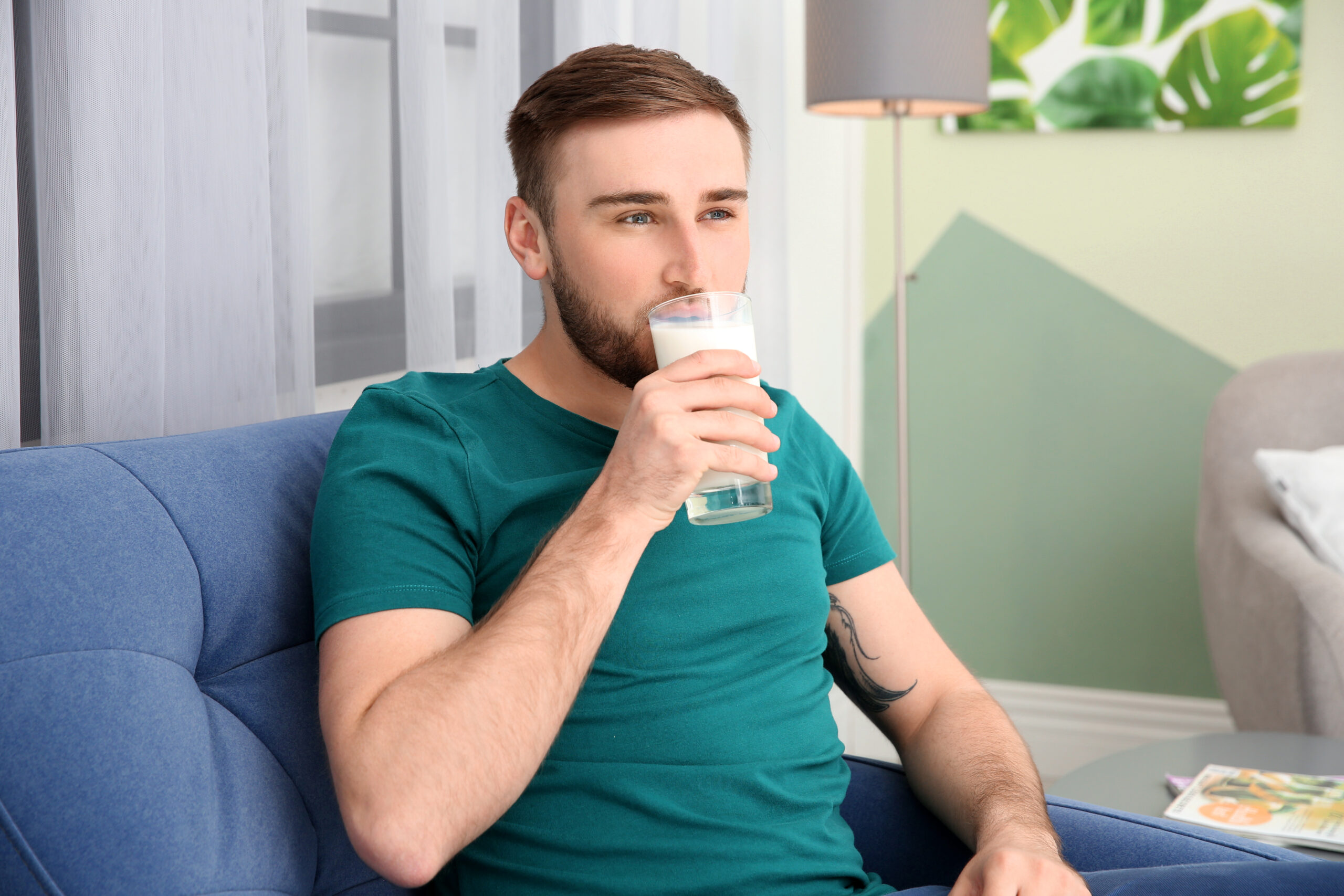 Young man drinking tasty milk at home