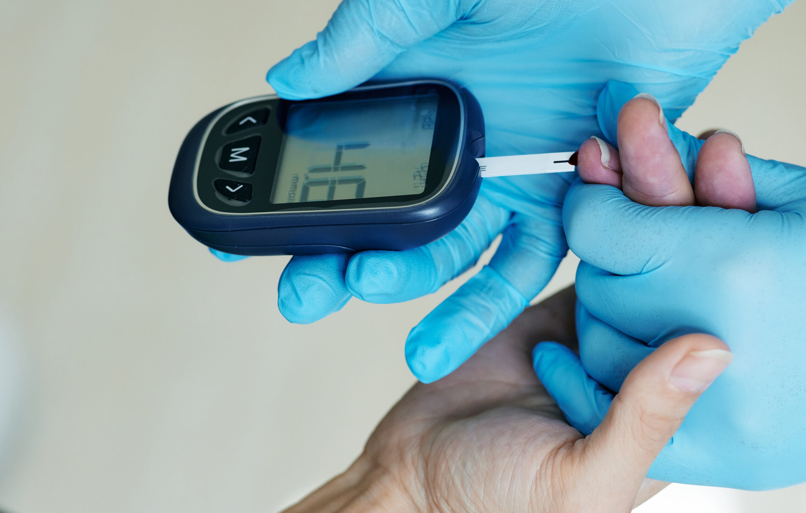 Medical worker checking blood glucose level of diabetic patient using glucometer, close-up. Endocrinology, blood sugar control